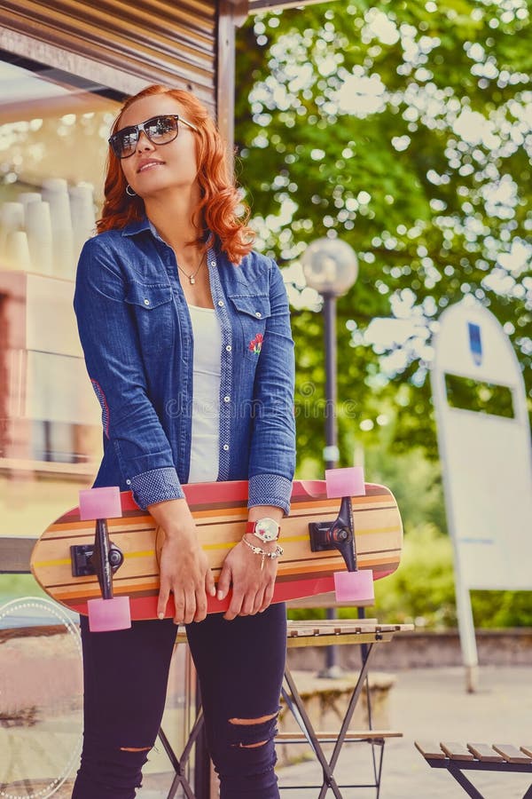 La femmina attraente della testarossa tiene Longboard immagini stock libere da diritti