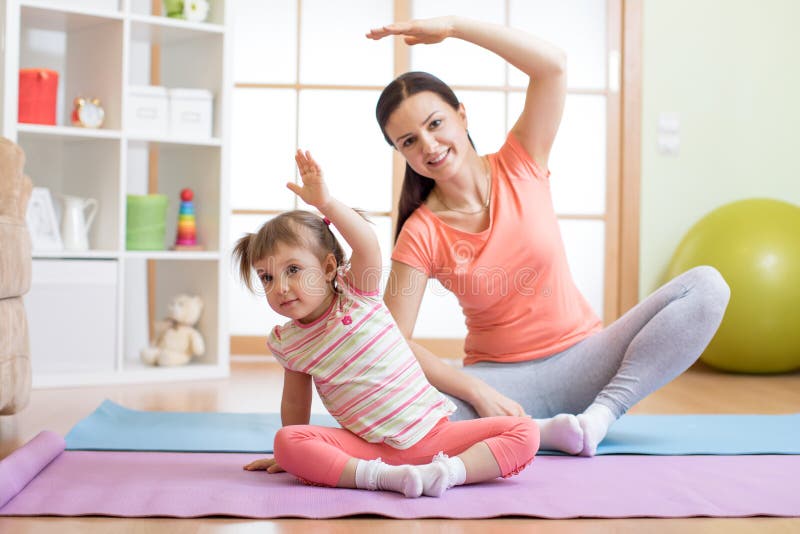 La figlia attiva del bambino e della madre è impegnata nella forma fisica, yoga, si esercita a casa