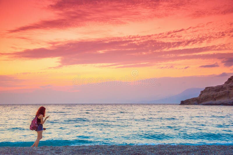 La fille apprécient le coucher du soleil étonnant à la plage de Matala photos libres de droits La fille apprécient le coucher du soleil étonnant à la plage de Matala photos libres de droits