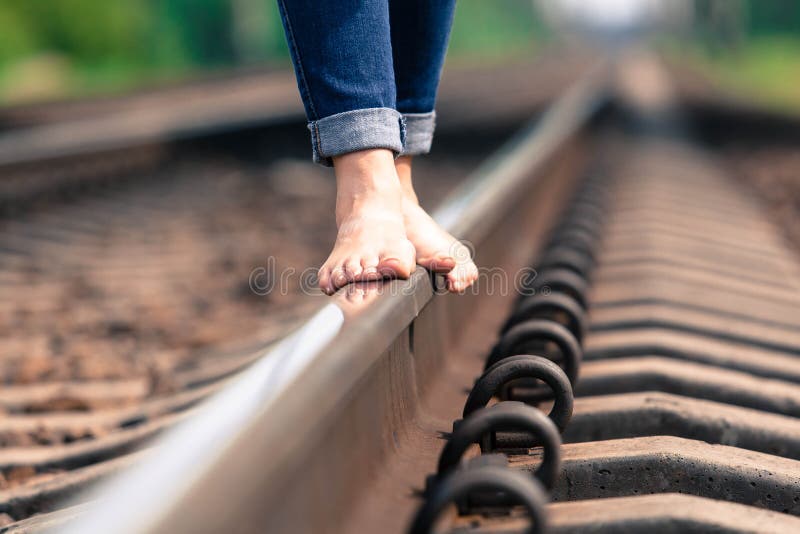 La fille aux pieds nus va par chemin de fer photographie stock libre de droits La fille aux pieds nus va par chemin de fer photographie stock libre de droits