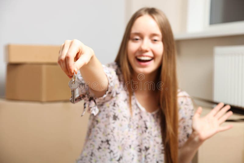 La fille avec des clés s'assied sur le fond des boîtes en carton en nouvel appartement photo stock La fille avec des clés s'assied sur le fond des boîtes en carton en nouvel appartement photo stock
