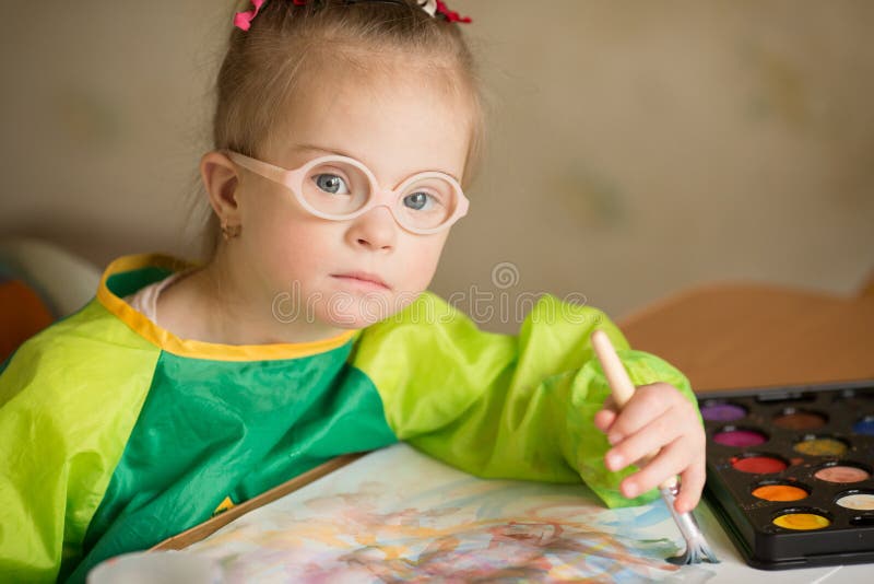 La fille avec la trisomie 21 dessine des peintures image libre de droits La fille avec la trisomie 21 dessine des peintures image libre de droits