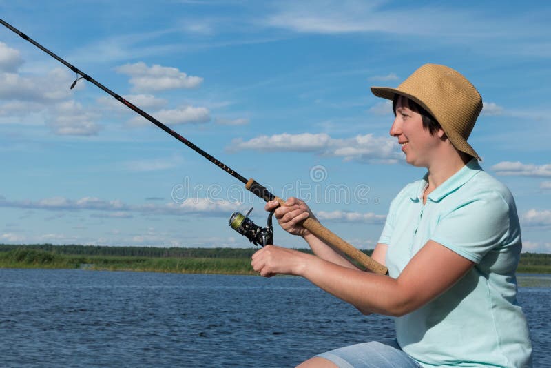 La fille avec un chapeau pêche sur une rivière un jour ensoleillé, plan rapproché photo libre de droits La fille avec un chapeau pêche sur une rivière un jour ensoleillé, plan rapproché photo libre de droits