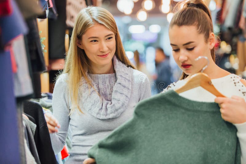 La fille avec une amie dans un magasin d'habillement a trouvé un chandail vert qu'elle a aimé images libres de droits La fille avec une amie dans un magasin d'habillement a trouvé un chandail vert qu'elle a aimé images libres de droits