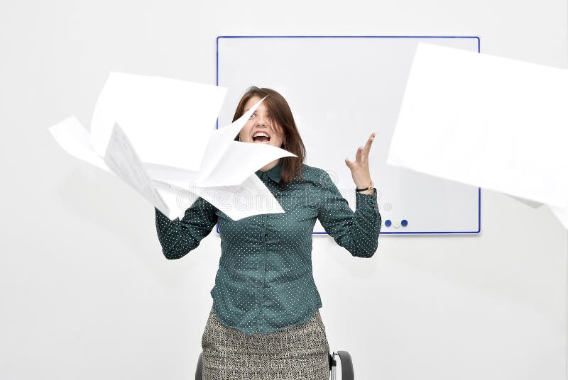 La fille châtain dans le bureau dans la rage a jeté des papiers et des documents photos stock La fille châtain dans le bureau dans la rage a jeté des papiers et des documents photos stock