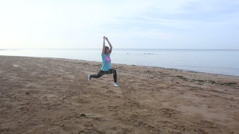 la fille commence à faire des exercices de matin sur la plage au lever de soleil