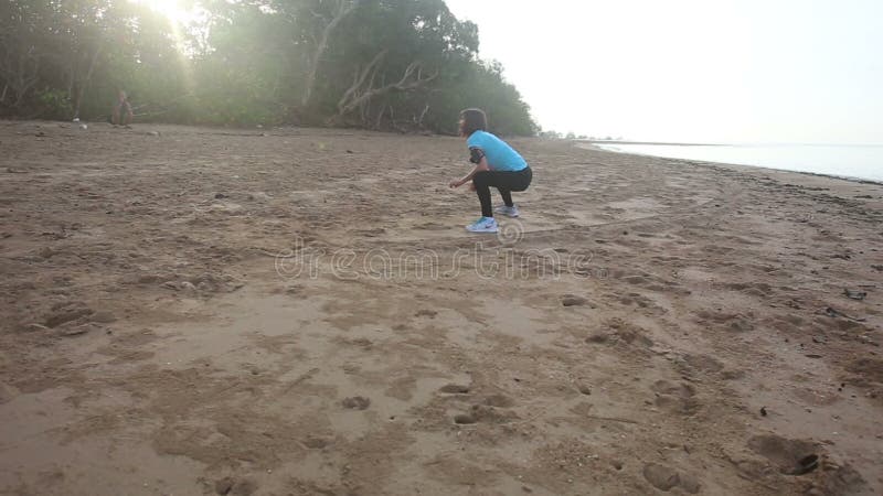 la fille commence à faire des exercices de matin sur la plage au lever de soleil