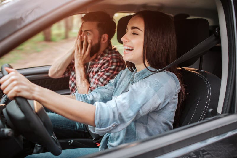 La fille conduit la voiture et rire Le type s'assied sans compter qu'elle Il est terrifié en raison de son entraînement du ` s d' images stock La fille conduit la voiture et rire Le type s'assied sans compter qu'elle Il est terrifié en raison de son entraînement du ` s d' images stock