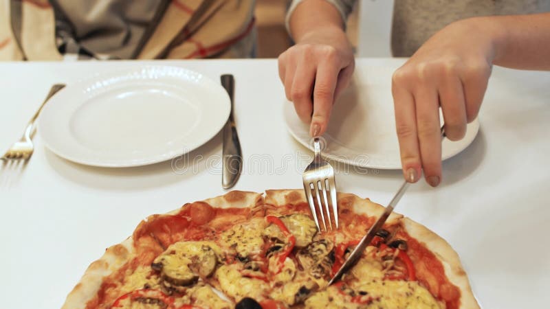 La fille coupe une pizza pour deux amis photo libre de droits La fille coupe une pizza pour deux amis photo libre de droits