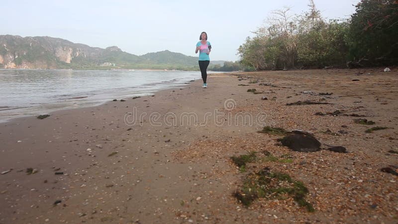 la fille de brune court loin sur la plage contre l'île