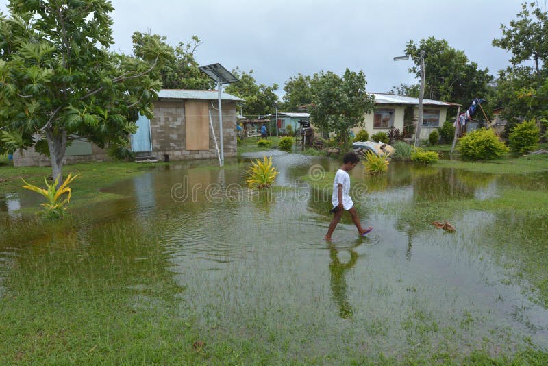 La fille de Fijian marche au-dessus de la terre inondée aux Fidji