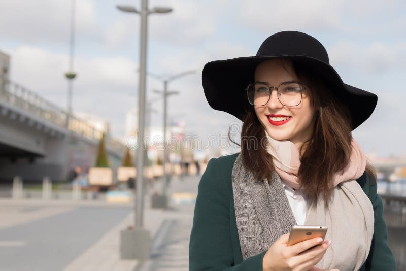 La fille de sourire gaie de brune dans les verres et le chapeau s'est habillée dedans FLB image stock La fille de sourire gaie de brune dans les verres et le chapeau s'est habillée dedans FLB image stock