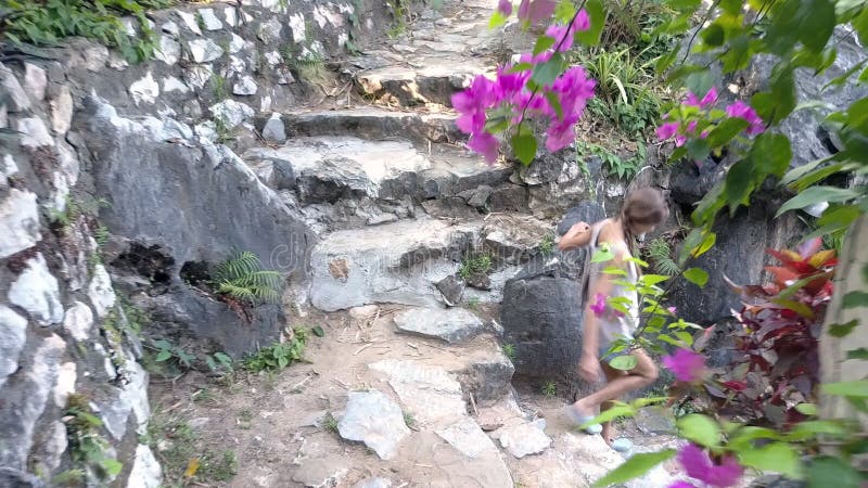 La fille de vue de côté descend les étapes en pierre menant à la cour