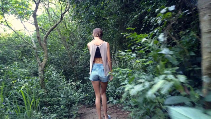 La fille de vue de postérieur descend les étapes en pierre dans la jungle