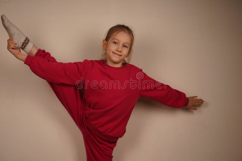 La fille en rouge montre l'équilibre de la pose d'hirondelle sur une jambe avec bras étendus. Son calme et sa concentration photographie stock