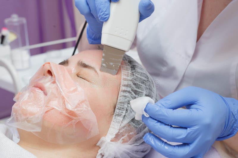 La fille est équipée de service de nettoyage de peau d'ultrason dans le salon de beauté image stock La fille est équipée de service de nettoyage de peau d'ultrason dans le salon de beauté image stock