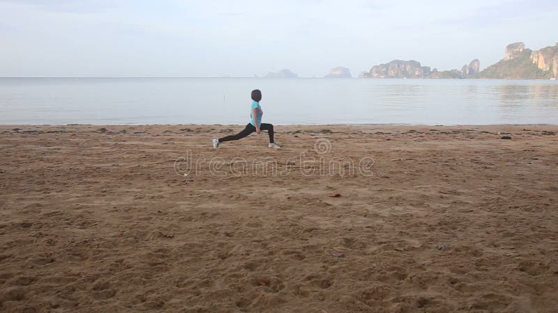 la fille fait des exercices de matin sur la plage à l'aube contre des falaises