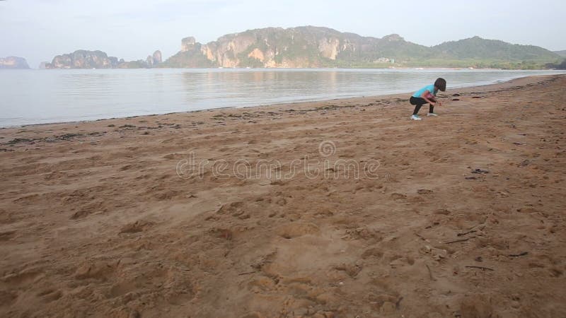 La fille fait le yoga et détend des muscles sur la plage au lever de soleil