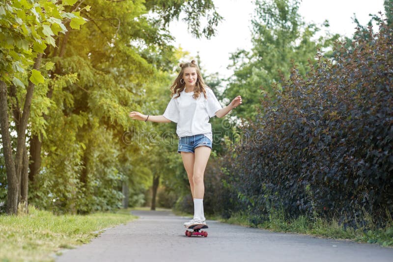 La fille gaie monte un panneau de patin en parc Le concept du mode de vie, loisirs images stock La fille gaie monte un panneau de patin en parc Le concept du mode de vie, loisirs images stock