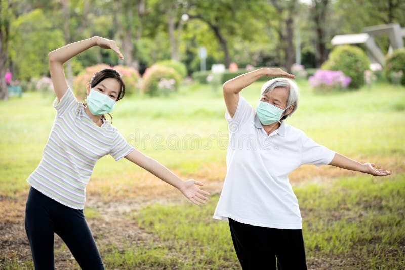 Happy child girl is doing exercise activity for the old elderly,healthy senior woman workout and wear face mask outside home after Coronavirus quarantine or Covid-19 lockdown,work out for health care. Happy child girl is doing exercise activity for the old elderly,healthy senior woman workout and wear face mask outside home after Coronavirus quarantine or Covid-19 lockdown,work out for health care