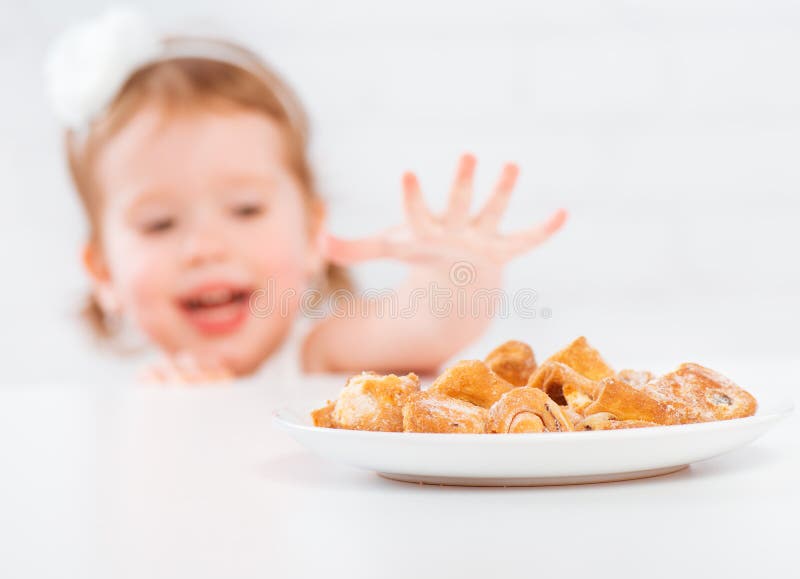 La fille heureuse d'enfant mange des biscuits et du lait images libres de droits La fille heureuse d'enfant mange des biscuits et du lait images libres de droits