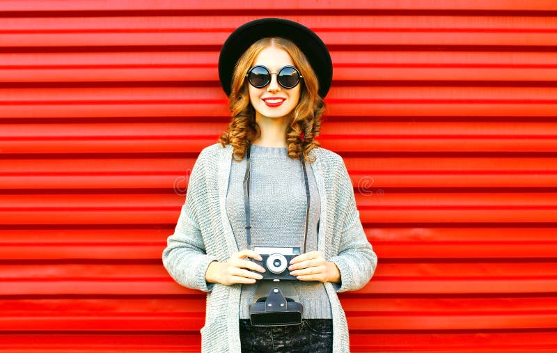 La fille heureuse de joli automne tient le rétro appareil-photo sur le fond rouge photos stock La fille heureuse de joli automne tient le rétro appareil-photo sur le fond rouge photos stock