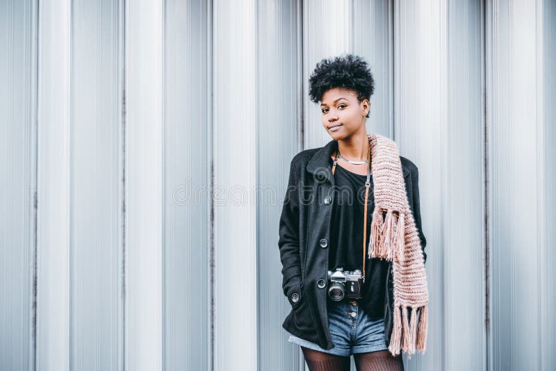 La fille noire avec le photocamera de vintage près a modelé le mur image libre de droits La fille noire avec le photocamera de vintage près a modelé le mur image libre de droits