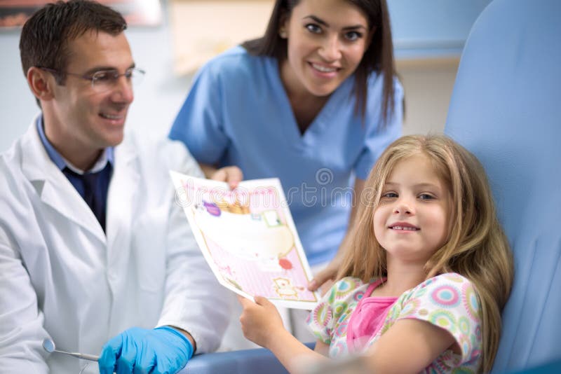 La fille reçoivent une carte de recommandation pour la bravoure au dentiste image stock La fille reçoivent une carte de recommandation pour la bravoure au dentiste image stock