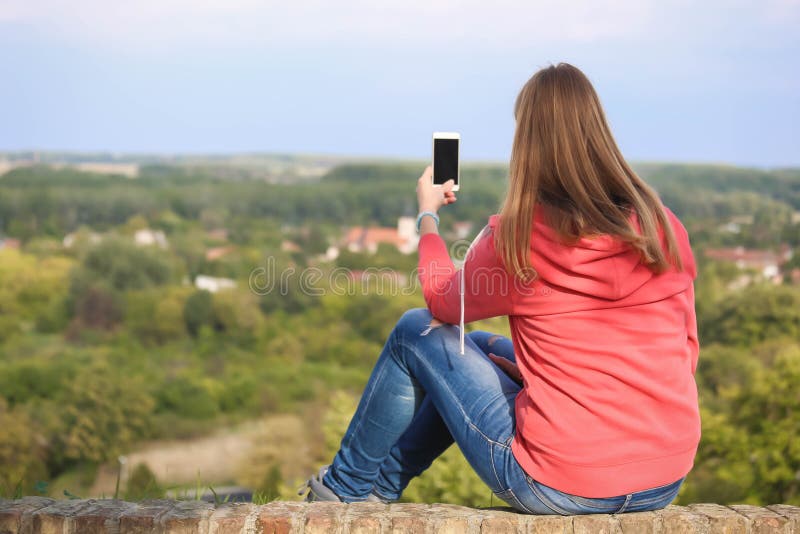 La fille s'asseyant sur un mur lui faisant face de retour et font la photo avec elle