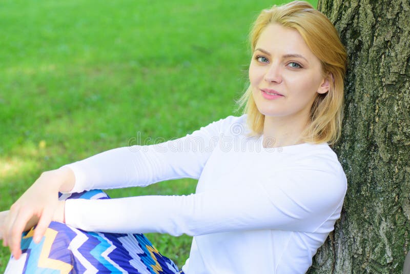 La fille s'asseyent sur le maigre d'herbe sur le tronc d'arbre détendant à l'arrière-plan de nature de vert d'ombre Coupure blond image libre de droits La fille s'asseyent sur le maigre d'herbe sur le tronc d'arbre détendant à l'arrière-plan de nature de vert d'ombre Coupure blond image libre de droits