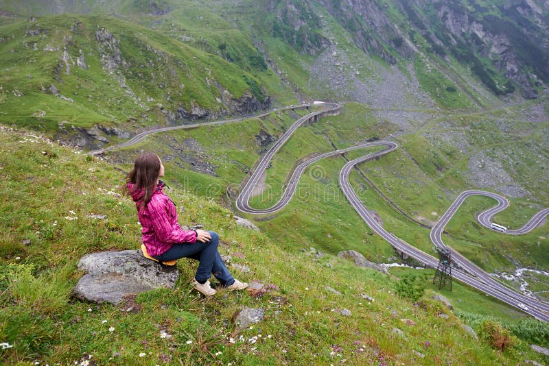 La fille s'assied sur la pierre appréciant le paysage merveilleux de montagne Route de Transfagarashan photos stock La fille s'assied sur la pierre appréciant le paysage merveilleux de montagne Route de Transfagarashan photos stock