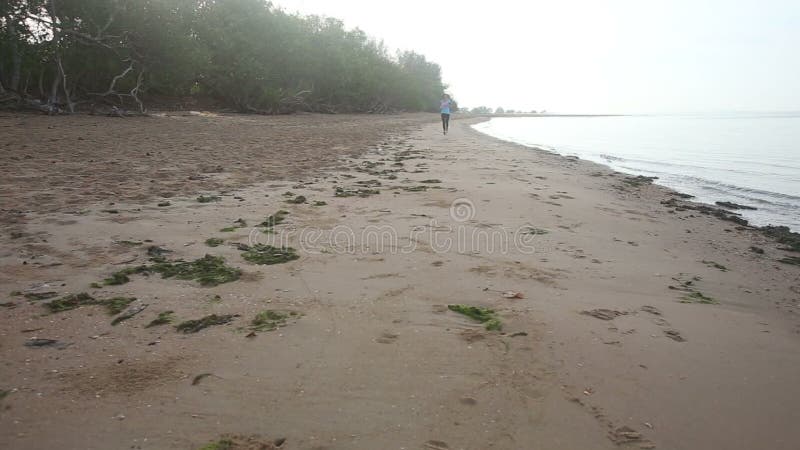 la fille s'échauffe dans l'espace à la plage à l'aube