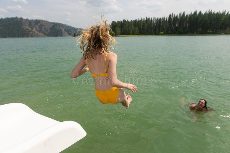 La fille sautant dans le lac de la glissière d'eau photographie stock La fille sautant dans le lac de la glissière d'eau photographie stock