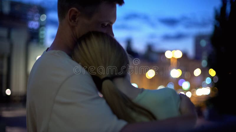 La fille se penche sur l'épaule de type, étreindre, regardant la ville de nuit, proximité, sécurité photographie stock libre de droits La fille se penche sur l'épaule de type, étreindre, regardant la ville de nuit, proximité, sécurité photographie stock libre de droits