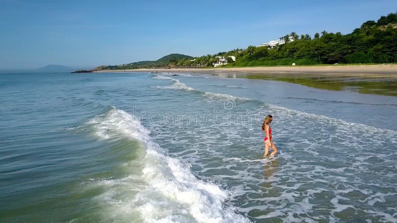 La fille sort outre de l'eau d'océan par les vagues mousseuses