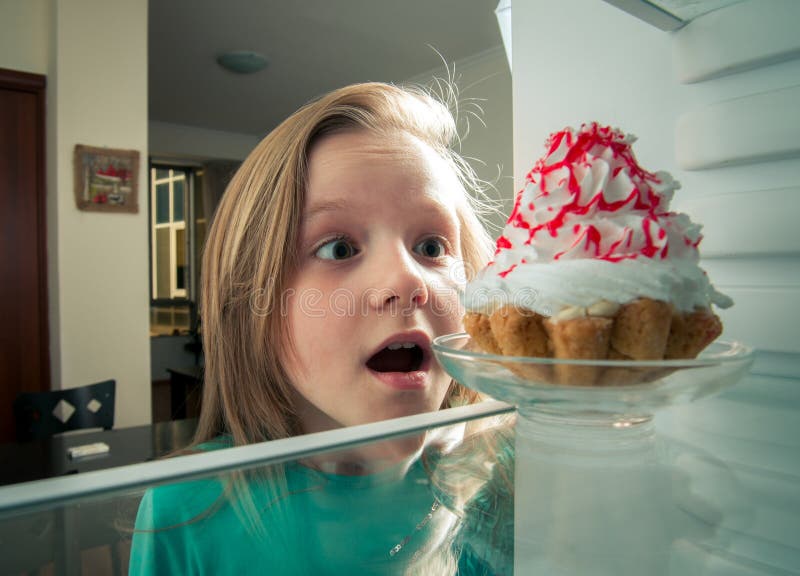 La fille voit le gâteau doux le réfrigérateur images stock La fille voit le gâteau doux le réfrigérateur images stock
