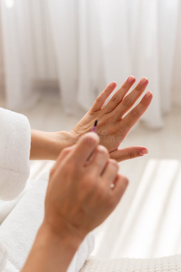 La fin d'une femme bien faite a peint ses clous pendant le matin, tout en se reposant sur le lit étant habillé dans une robe de c photos libres de droits La fin d'une femme bien faite a peint ses clous pendant le matin, tout en se reposant sur le lit étant habillé dans une robe de c photos libres de droits