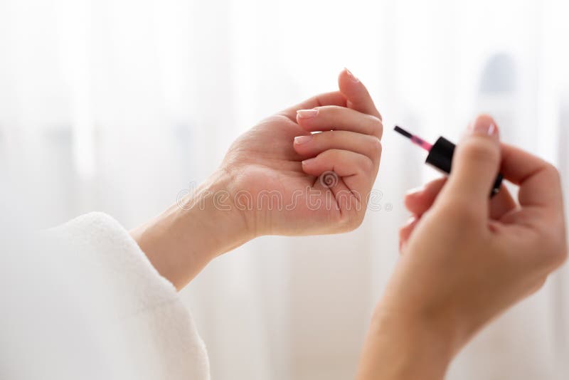 La fin d'une femme bien faite a peint ses clous pendant le matin, tout en se reposant sur le lit étant habillé dans une robe de c photographie stock La fin d'une femme bien faite a peint ses clous pendant le matin, tout en se reposant sur le lit étant habillé dans une robe de c photographie stock