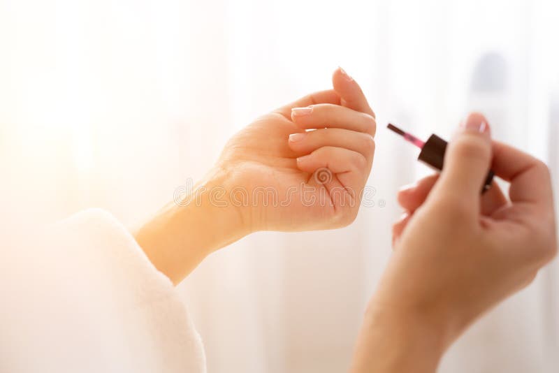 La fin d'une femme bien faite a peint ses clous pendant le matin, tout en se reposant sur le lit étant habillé dans une robe de c photos libres de droits La fin d'une femme bien faite a peint ses clous pendant le matin, tout en se reposant sur le lit étant habillé dans une robe de c photos libres de droits
