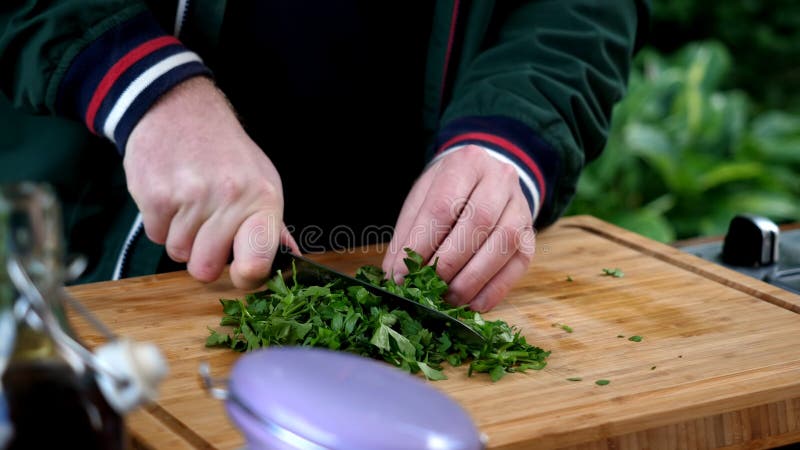 La fin vers le haut de l'homme fait cuire la table en bois de persil image stock La fin vers le haut de l'homme fait cuire la table en bois de persil image stock