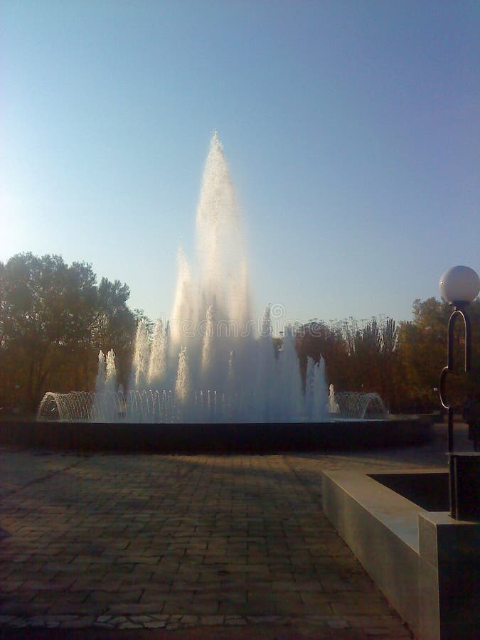 La fontana del parco Majestic con più getti d'acqua al tramonto contro gli alberi immagini stock libere da diritti