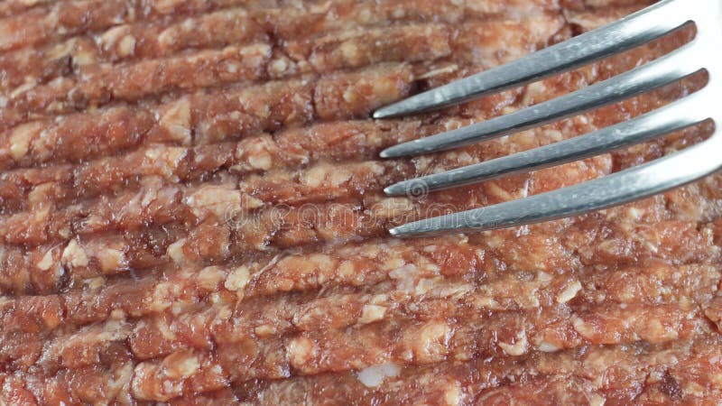 La forcella spende sulla carne tritata del pollo crudo, vista superiore del colpo del primo piano fotografia stock La forcella spende sulla carne tritata del pollo crudo, vista superiore del colpo del primo piano fotografia stock