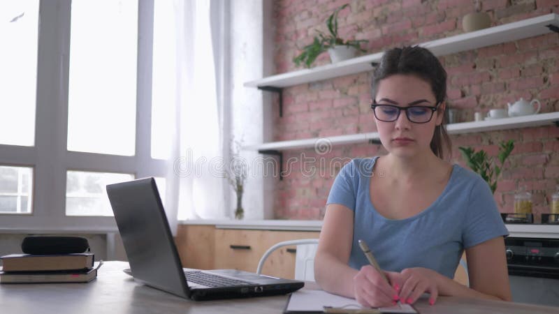 La formation en ligne, jeune femme belle en verres utilisent l'ordinateur portable et Ã©crivent des notes dans le presse-papiers