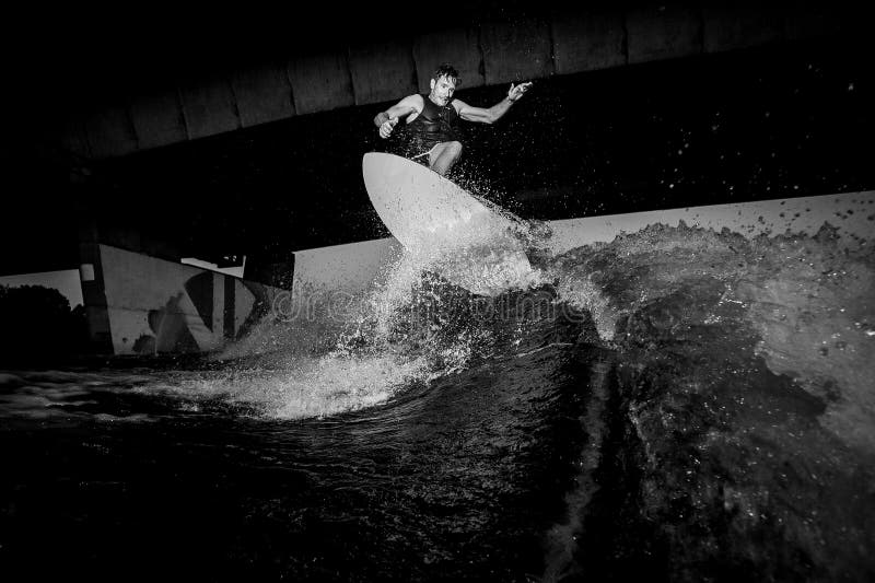 La foto blanco y negro del montar a caballo activo del wakesurfer en el río agita fotos de archivo libres de regalías La foto blanco y negro del montar a caballo activo del wakesurfer en el río agita fotos de archivo libres de regalías