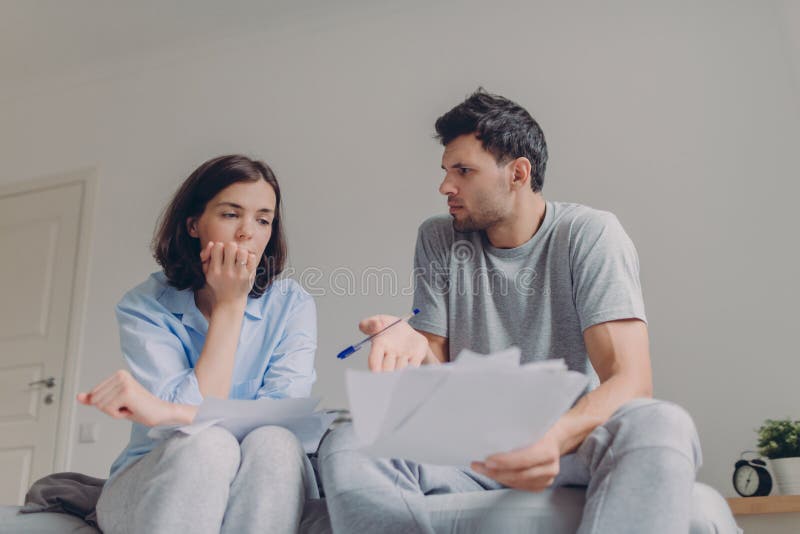 La foto de los pares jovenes agotadores de la familia tiene muchas deudas, prepara informe fincial, piensa en convertirse del fut imagen de archivo libre de regalías La foto de los pares jovenes agotadores de la familia tiene muchas deudas, prepara informe fincial, piensa en convertirse del fut imagen de archivo libre de regalías