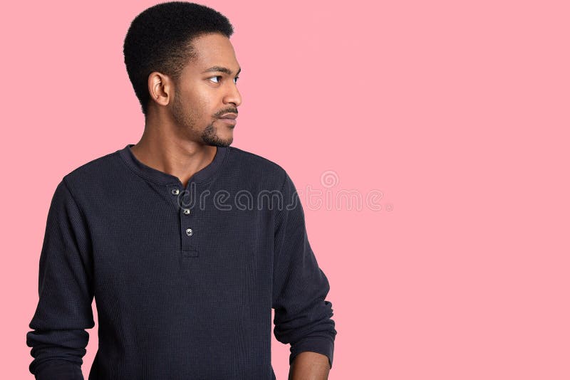 La foto del hombre hermoso se coloca de lado, mira seriamente a un lado, tiene rastrojo, piel oscura, lleva la ropa casual, conce fotos de archivo La foto del hombre hermoso se coloca de lado, mira seriamente a un lado, tiene rastrojo, piel oscura, lleva la ropa casual, conce fotos de archivo