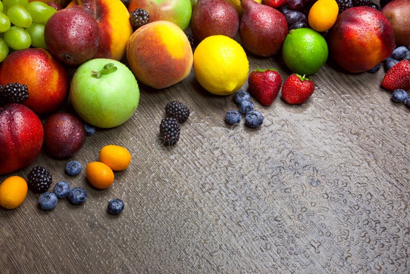 La frontera de frutas mezcladas con agua cae en textura de madera imagen de archivo La frontera de frutas mezcladas con agua cae en textura de madera imagen de archivo