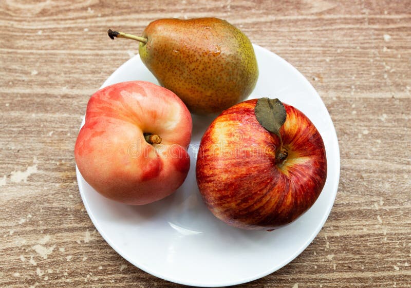 La frutta fresca sta trovando su un fondo marrone in un piatto bianco immagine stock La frutta fresca sta trovando su un fondo marrone in un piatto bianco immagine stock