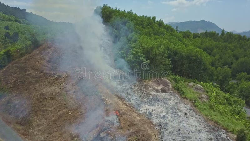 La fumée du feu commandé se lève au-dessus de la route en montagne