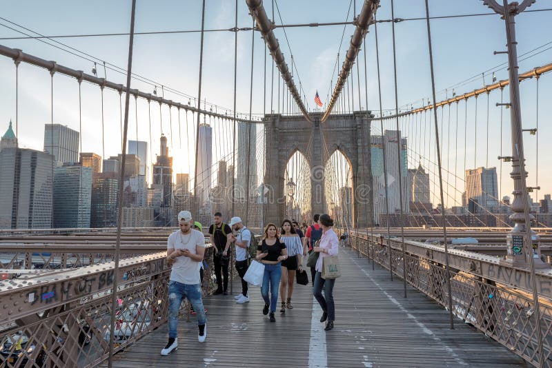 La gente cammina attraverso il ponte di Brooklyn al tramonto a New York fotografie stock libere da diritti La gente cammina attraverso il ponte di Brooklyn al tramonto a New York fotografie stock libere da diritti